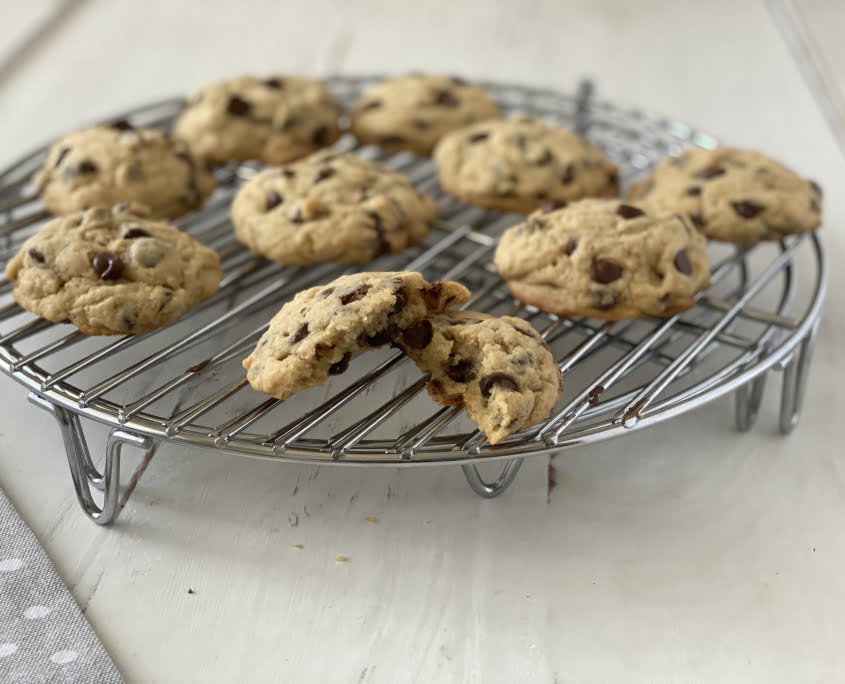 Chocolate chip cookies on wire cooling rack, cookie broken showing gooey insides
