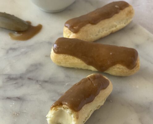 Salted Maple Caramel Eclairs with a bite taken from one - Pure Maple
