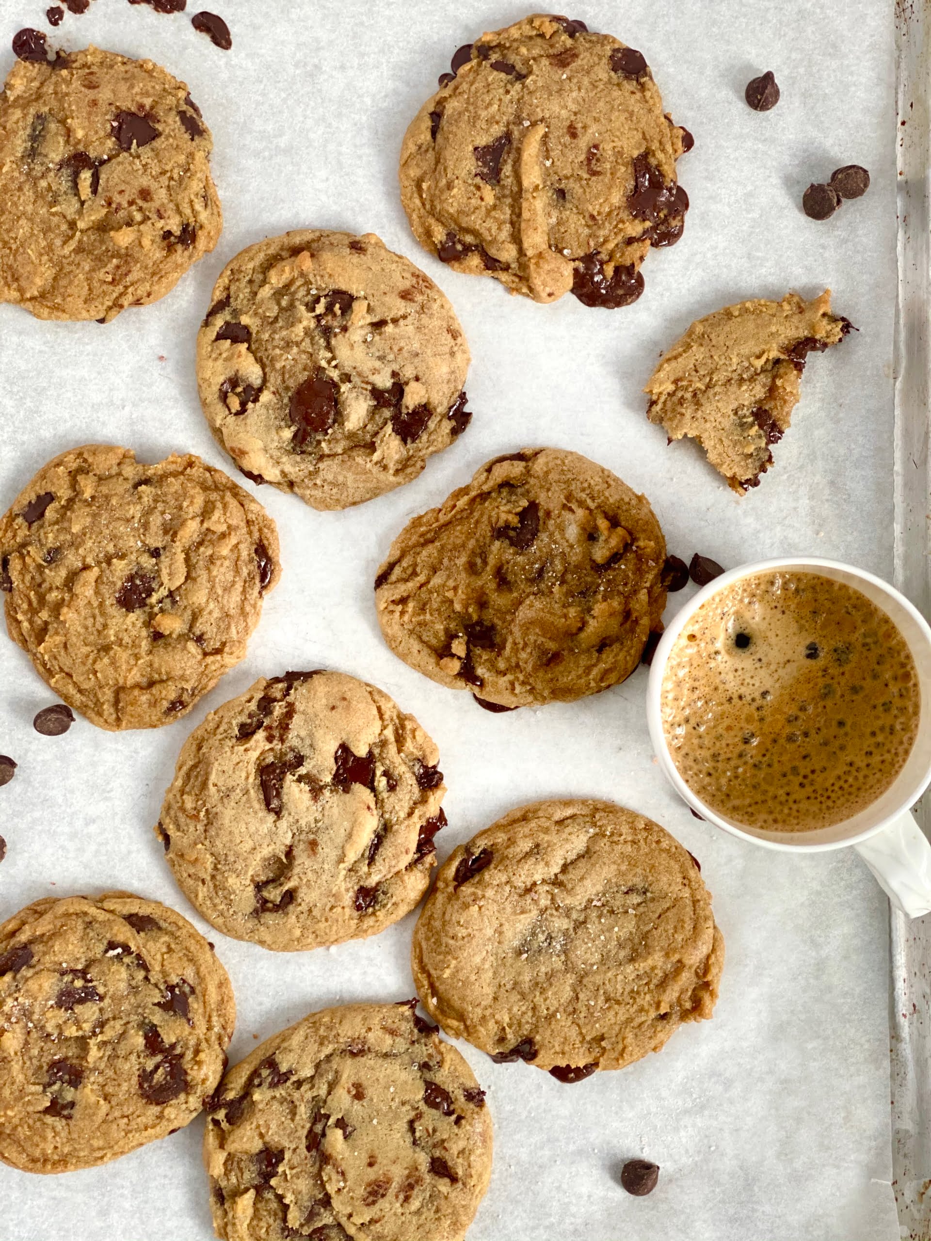 Vegan Chocolate Chip Cookies on a baking tray with a cup of coffee - Pure Maple
