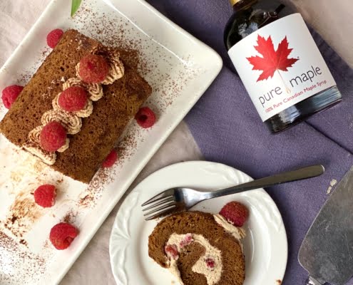 Maple Espresso Roll with Raspberries showing a slice cut and maple syrup bottle - Pure Maple