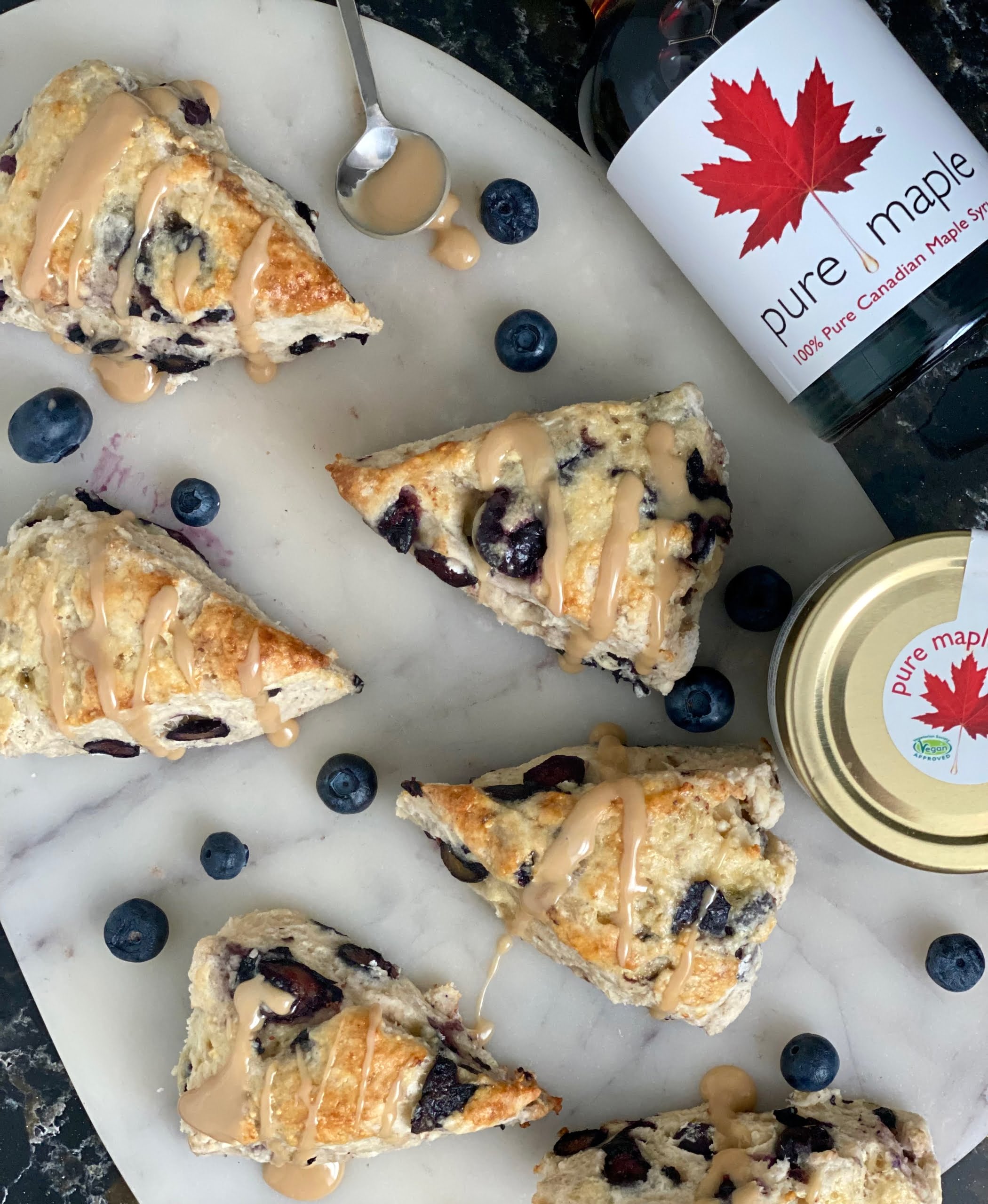 Maple Blueberry Scones drizzled with maple and a maple syrup bottle and maple butter jar on one 1 side