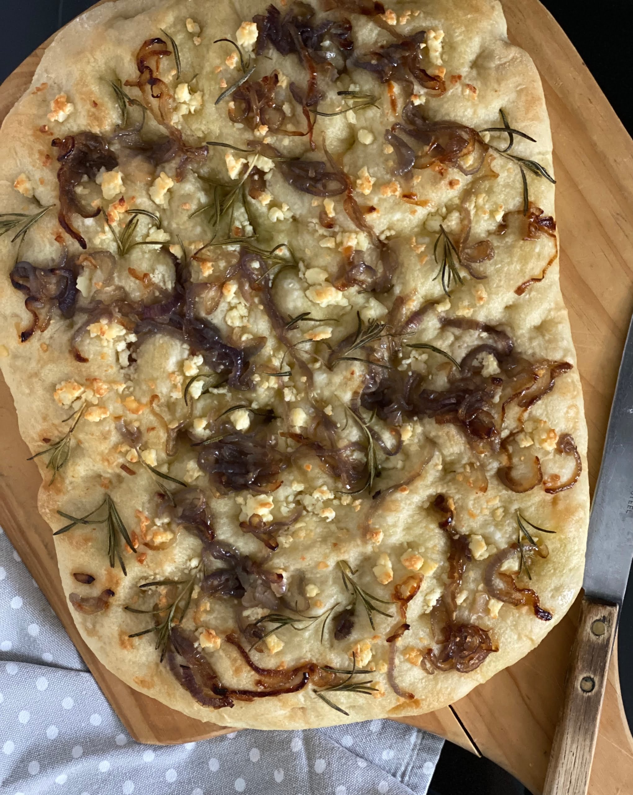 Maple Onion and Feta Focaccia on a cutting board with a knife to the side - Pure Maple