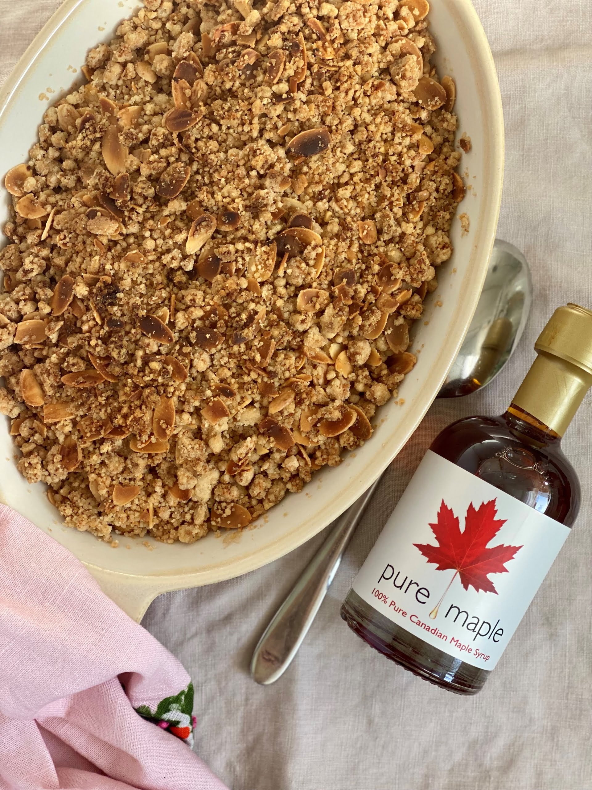 Vegan apple crumble with maple syrup bottle to the side