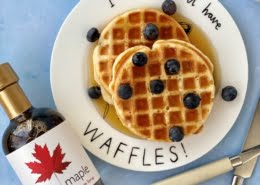 Waffles served with maple syrup and blueberries and pure maple syrup bottle