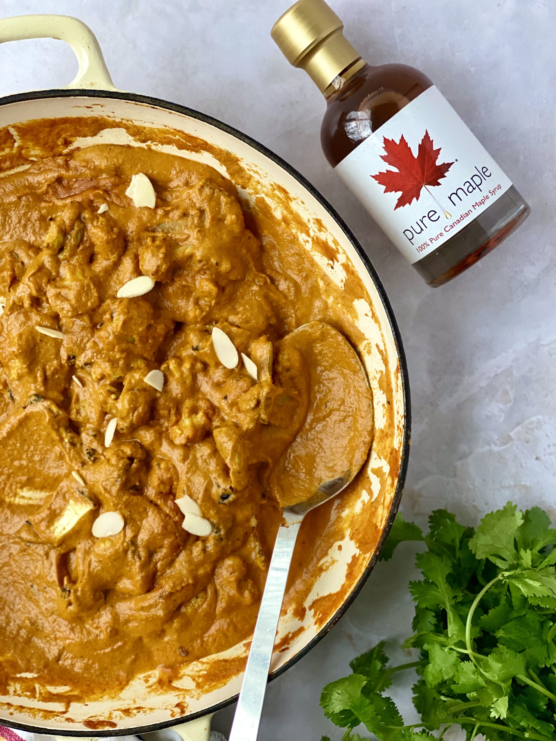 Cauliflower maple korma with flaked almonds a bunch of fresh coriander and a bottle of maple syrup