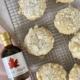 Almond cookies on a wire rack with a maple syrup at the side